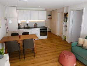 A modern kitchen with white cabinets, a dining table with chairs, and a built-in oven. - Am Bellevuegässli Appartement/Fewo, Bad, WC, 1 Schlafraum 2,5 - Zimmerwohnung by Interhome (Adelboden)