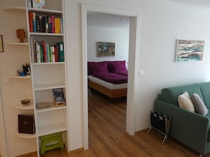 A room with a bed, a green sofa, a bookshelf, and a painting on the wall. - Am Bellevuegässli Appartement/Fewo, Bad, WC, 1 Schlafraum 2,5 - Zimmerwohnung by Interhome (Adelboden)