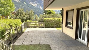 A building with a patio area, a wooden fence, and a mountain view. - Rapunzel Paterre B25 Appartement/Fewo, Dusche, WC, 2 Schlafräume by Interhome (Adelboden)