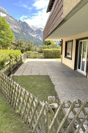 Ein Gebäude mit einer Terrasse, einem Holzzaun und Blick auf die Berge.