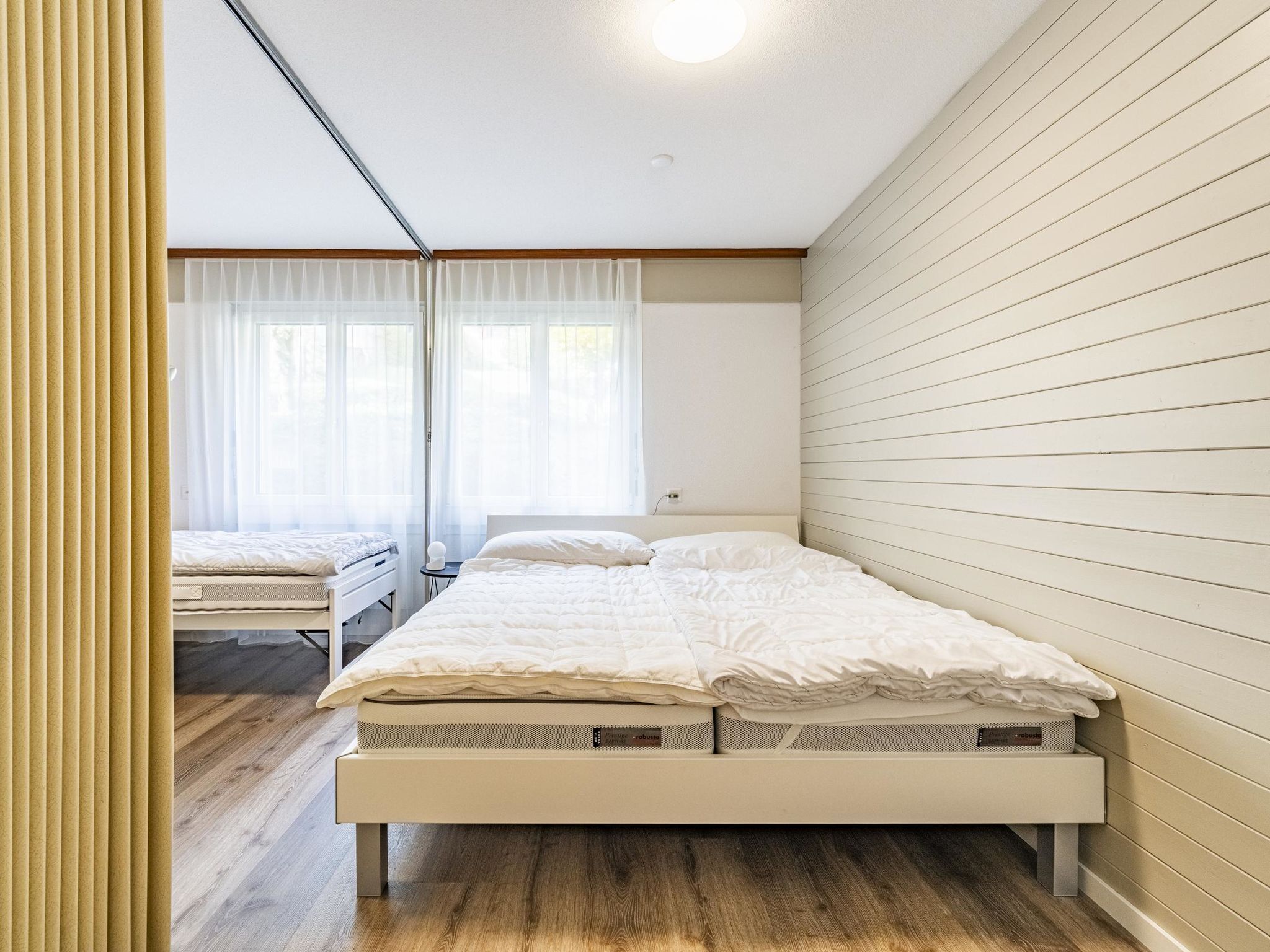 Ein Schlafzimmer mit einem Bett, einem Nachttisch und einem Fenster mit Vorhängen.