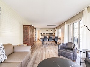A modern living room with a sofa, a leather armchair, and a dining area with a table and chairs. - Rapunzel Paterre B25 Appartement/Fewo, Dusche, WC, 2 Schlafräume by Interhome (Adelboden)