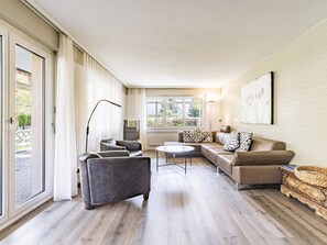Ein geräumiges Wohnzimmer mit einer Sofagarnitur, einem Couchtisch und einer Stehlampe.