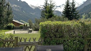 A table set outdoors with a view of mountains, a wooden fence, and a hedge. - Rapunzel Paterre B25 Appartement/Fewo, Dusche, WC, 2 Schlafräume by Interhome (Adelboden)