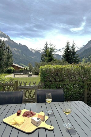 Ein Tisch im Freien mit Blick auf Berge, einen Holzzaun und einen Heckenstreifen.