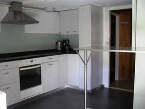 A modern kitchen with white cabinets, a stainless steel range, and a coffee maker. - Hagrösli Appartement/Fewo, Dusche, WC, 1 Schlafraum 2-Zimmerwohnung by Interhome (Adelboden)