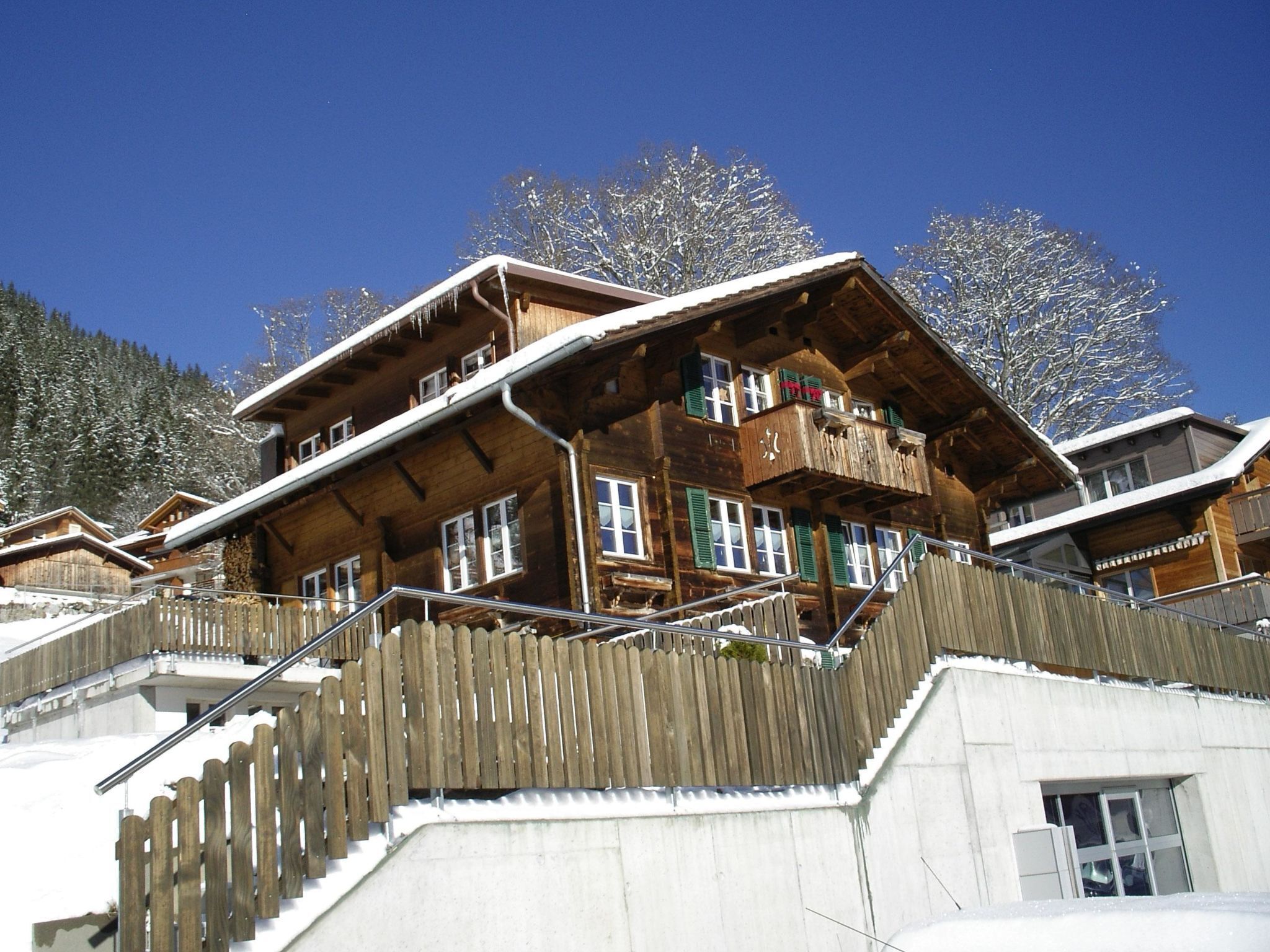 A wooden chalet with multiple balconies and a wooden fence.