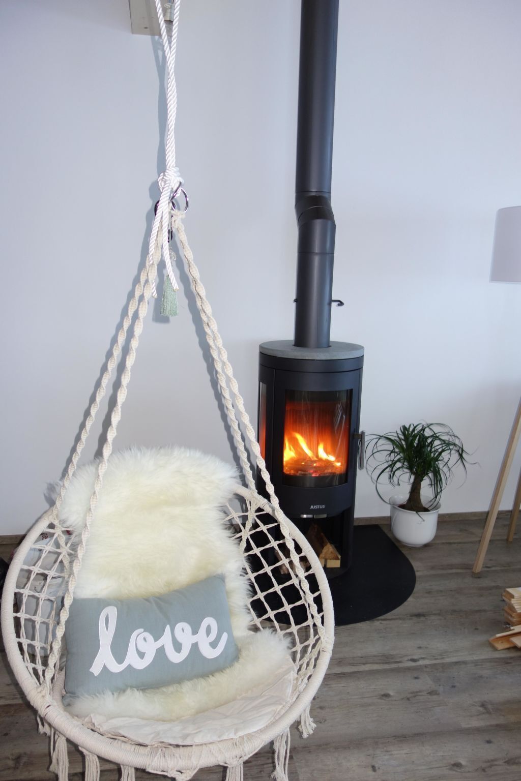Ein Zimmer mit Hängekorbschaukel, Holzofen und kleiner Topfpflanze.