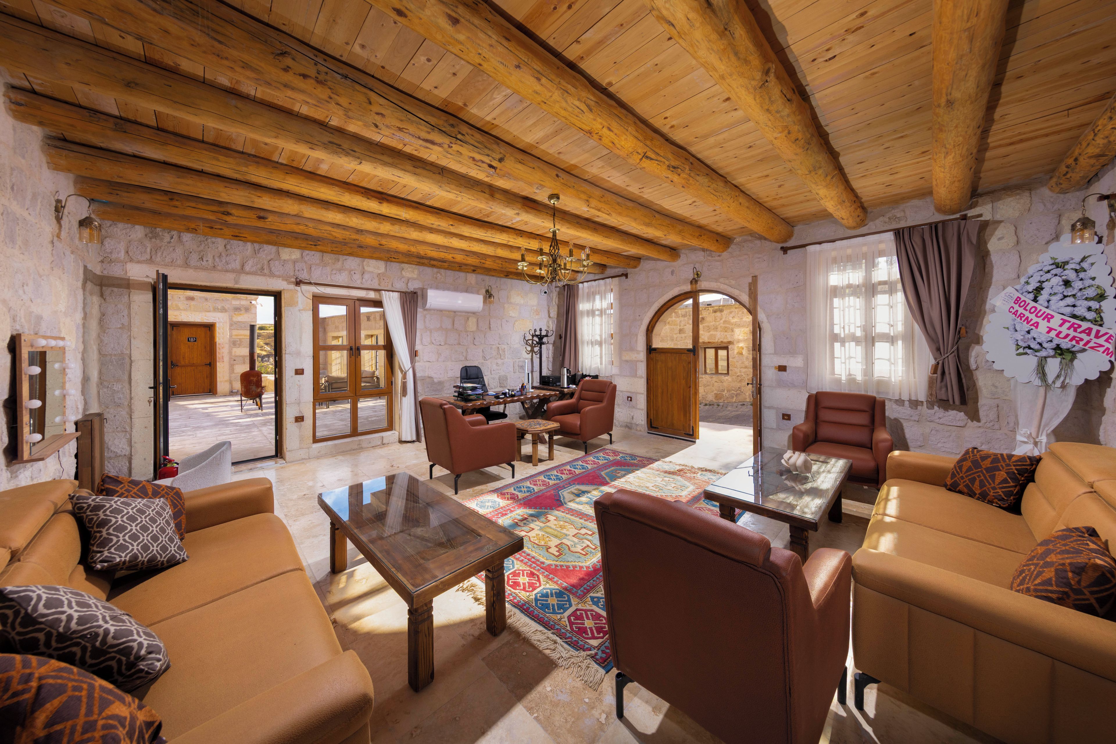 Amplia sala de estar con techo de madera alto, paredes de piedra y una combinación de muebles de cuero y tela.