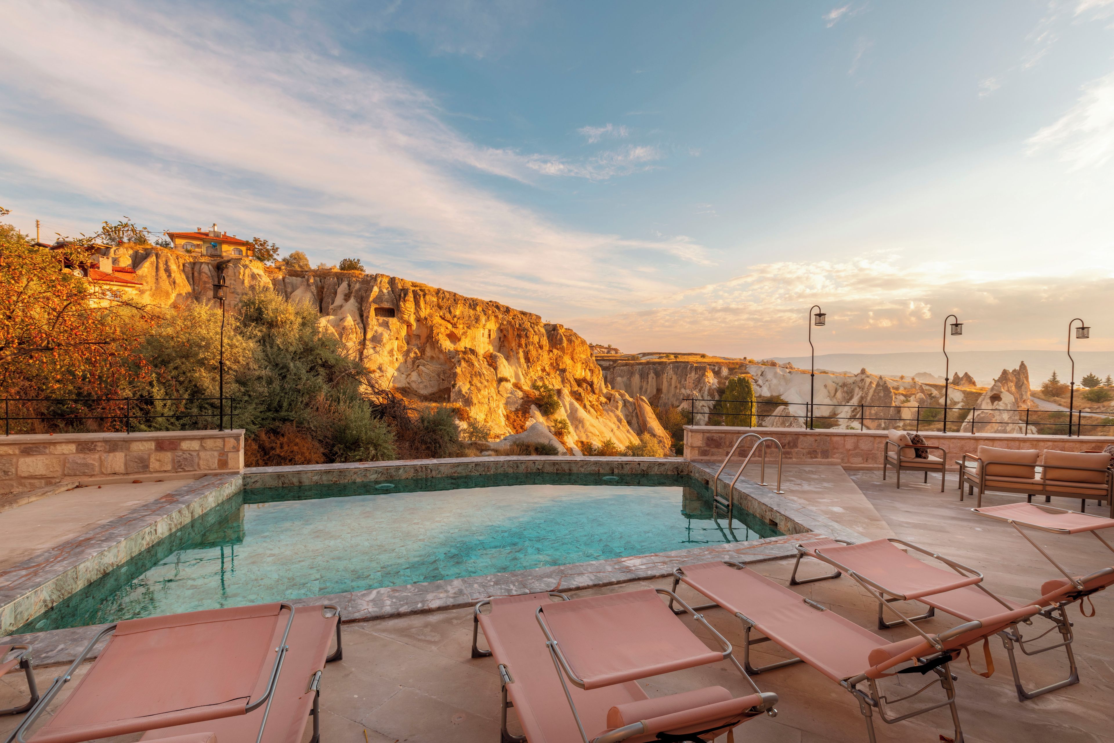 A pool area with lounge chairs and a view of a cliff.