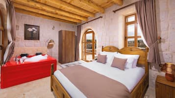 A bedroom with a wooden bed, a red bath, and stone walls.