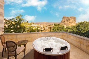 A hot tub with two towels, a chair, and a view of a rocky landscape.