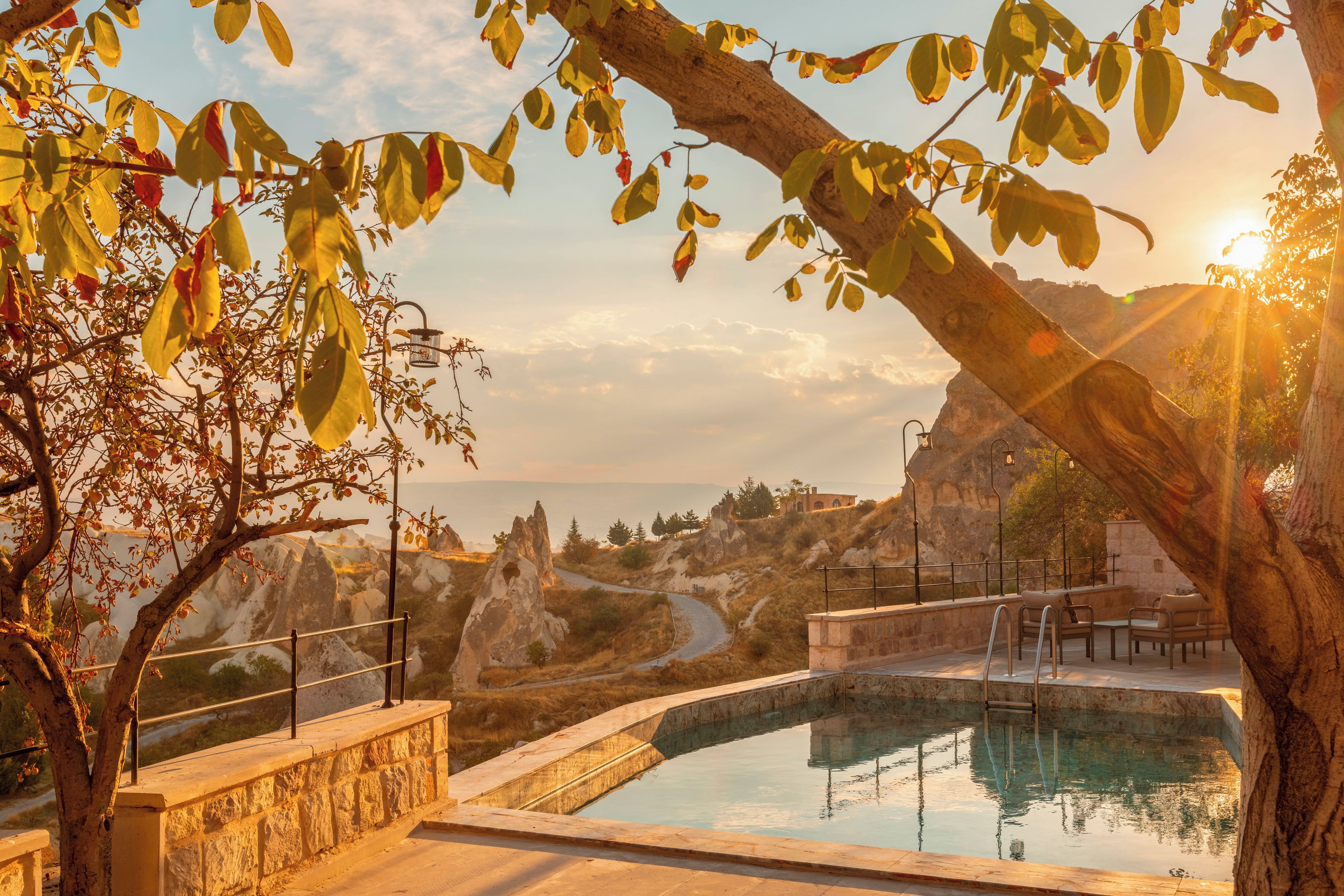 Zona de piscina con pared de piedra, vista a terreno rocoso y cielo despejado.