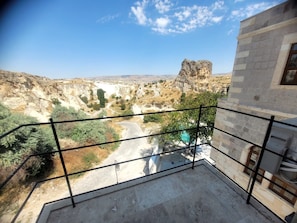 A balcony with a view of a rocky landscape and a building with a stone facade.