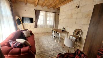 Una sala de estar acogedora con un sofá rojo, un tapete estampado, una mesa de madera y un televisor montado en la pared.