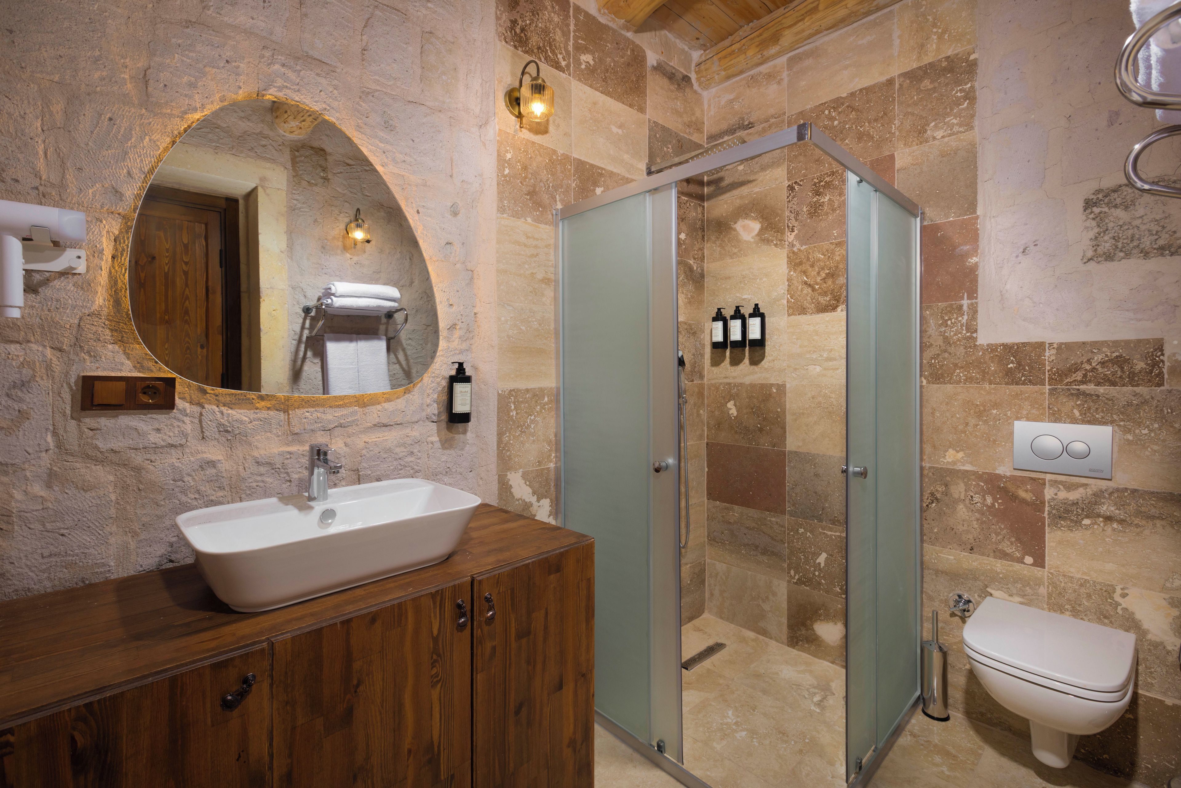 Un baño con una bañera independiente, un tocador de madera, una ducha con mampara de vidrio y un inodoro.