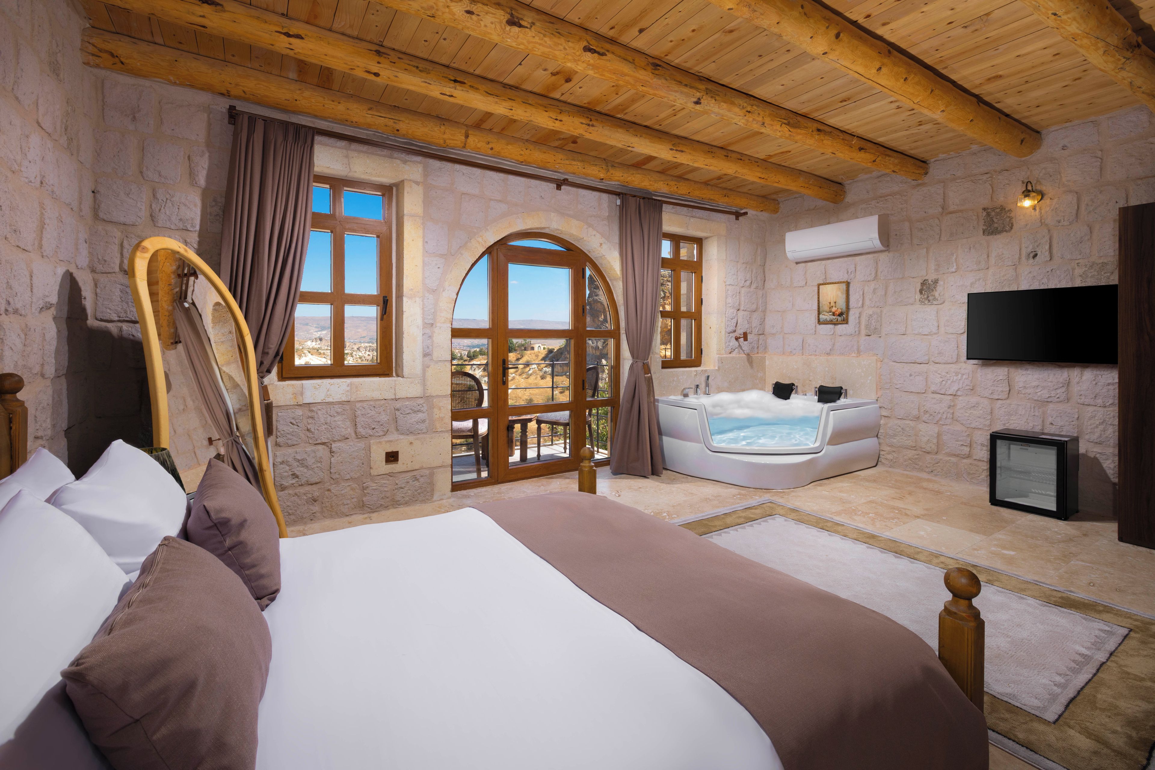 Un dormitorio con una cama grande, una bañera y un televisor.