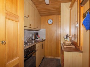 Eine kleine Küche mit Holzausstattung, einem Herd und einer Uhr an der Wand.