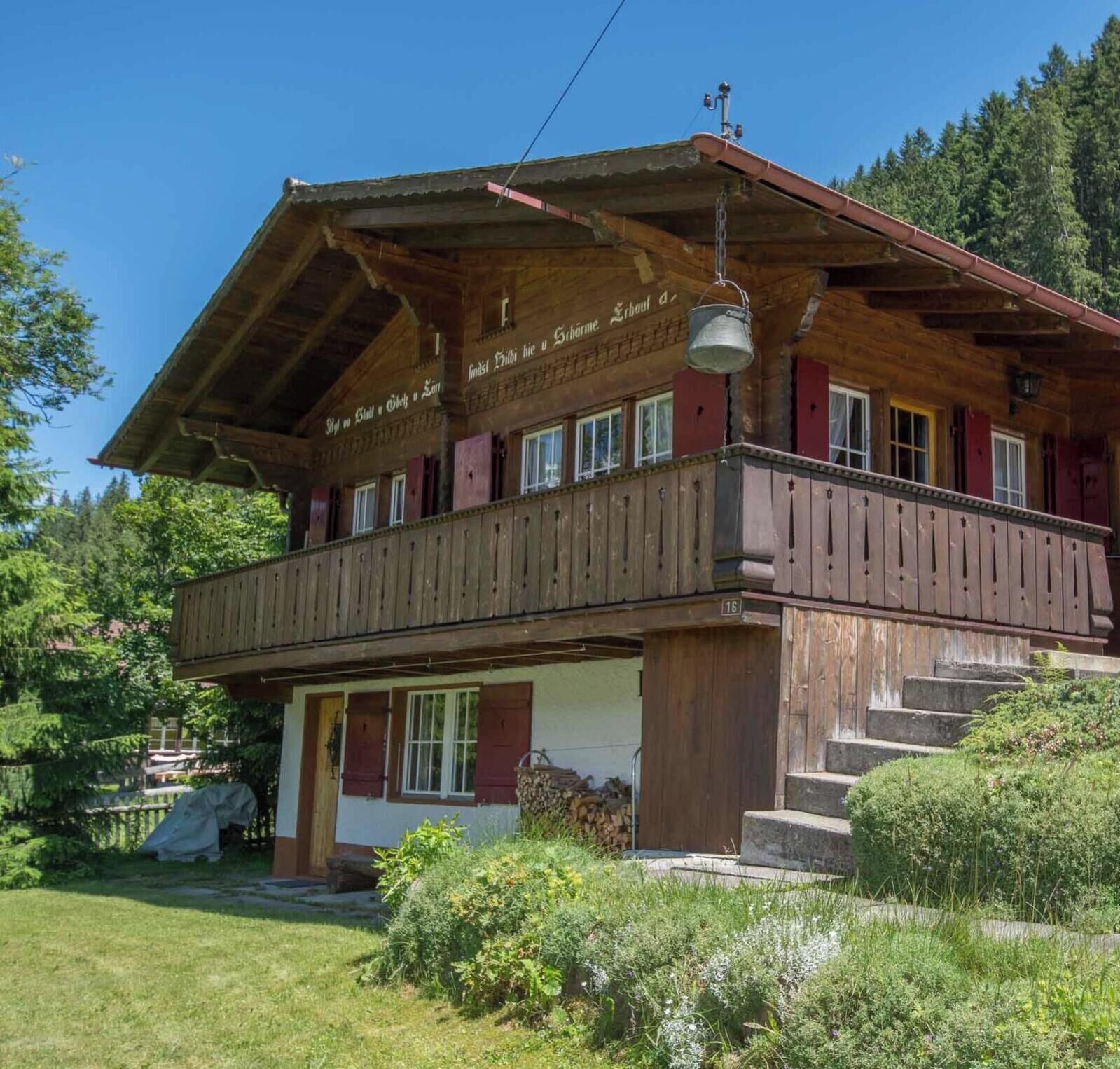 Ein traditionelles Holzchalet mit Balkon, Hauseingang und Treppe zum Obergeschoss.