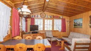 A wooden interior with a dining table, chairs, a sofa, a television, and a painting on the wall. - Chalet Iris Appartement/Fewo, Dusche, WC, 2 Schlafräume 3-Zimmerwohnung by Interhome (Adelboden)