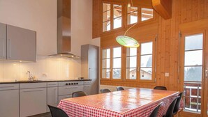 Una cucina moderna con mobili bianchi, una cappa in acciaio inossidabile e un'area pranzo con tovaglia a scacchi.