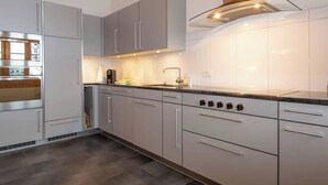 Una cucina moderna con elettrodomestici in acciaio inossidabile, mobili grigi e un piano di lavoro nero.