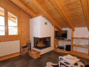 Ein gemütliches Zimmer mit Kamin, Fernseher auf einem Holzboden und einem Kuhfellteppich.