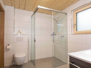 Ein modernes Badezimmer mit Duschkabine aus Glas, Toilette und Waschbecken.