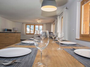 A dining table set with plates, glasses, and cutlery, with a view of mountains through the window. - Schützenrain 1. Stock Appartement/Fewo, Bad, WC, 3 Schlafräume by Interhome (Adelboden)