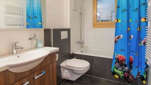 A bathroom with a bathtub, a toilet, and a sink. - Schützenrain 1. Stock Appartement/Fewo, Bad, WC, 3 Schlafräume by Interhome (Adelboden)