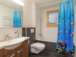 A bathroom with a bathtub, a toilet, and a sink. - Schützenrain 1. Stock Appartement/Fewo, Bad, WC, 3 Schlafräume by Interhome (Adelboden)