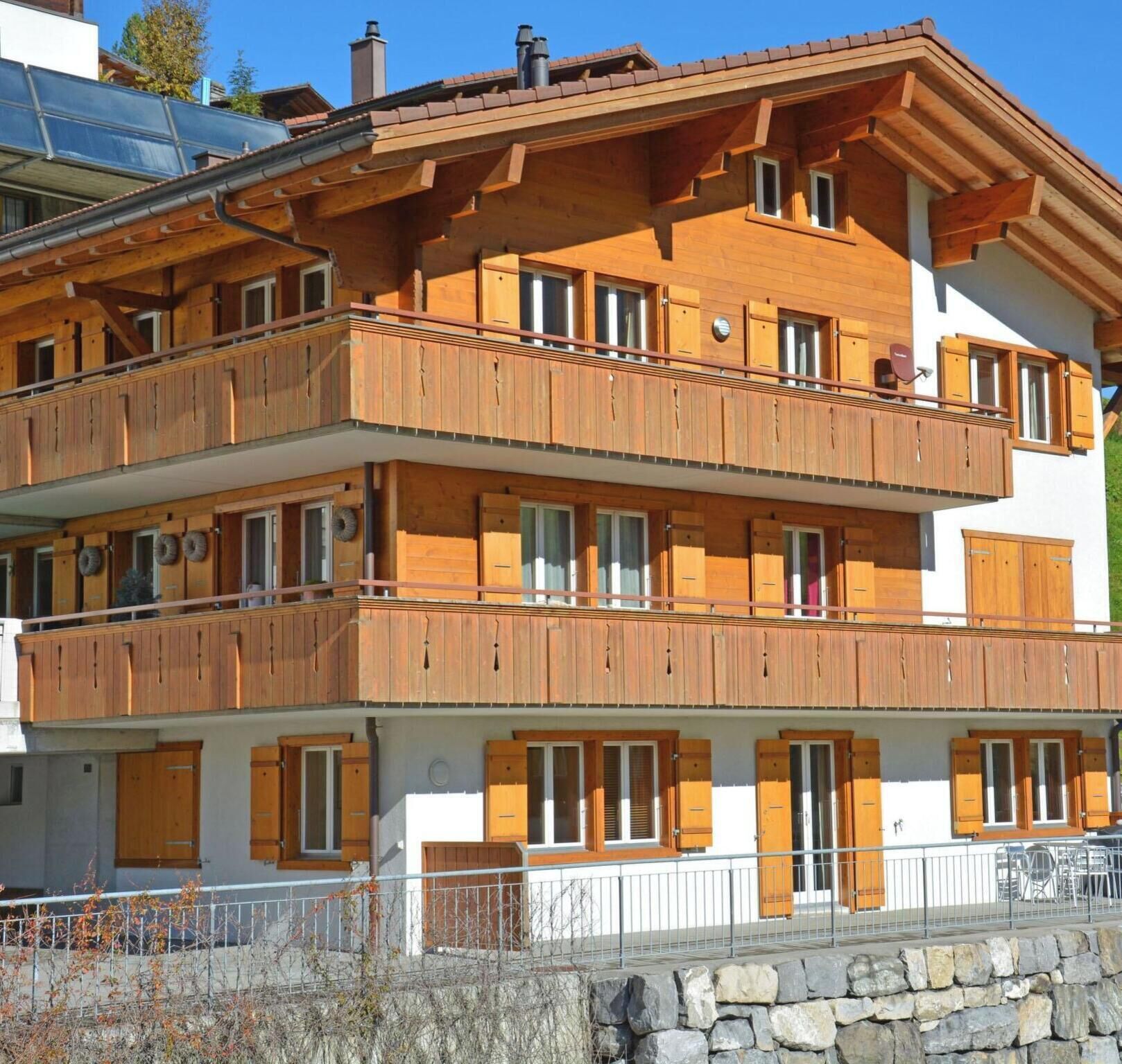 A multi-story building with wooden balconies and large windows.