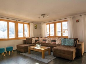 A cozy living room with a brown sectional sofa, a wooden coffee table, and two blue armchairs. - Schützenrain 1. Stock Appartement/Fewo, Bad, WC, 3 Schlafräume by Interhome (Adelboden)