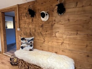 Ein Zimmer mit einer Holzwand, einer weißen, flauschigen Bank und einem Gemälde einer Berglandschaft.