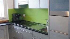 A modern kitchen with grey cabinets, a stainless steel sink, and a built-in oven. - Helios Appartement/Fewo, Dusche, WC, 3 Schlafräume 4-Zimmerwohnung by Interhome (Adelboden)
