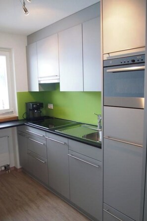 Eine moderne Küche mit grauen Schränken, einer Edelstahl-Spüle und einem eingebauten Backofen.