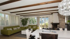 A spacious living area with a green sofa, a dining table, and a fireplace. - Helios Appartement/Fewo, Dusche, WC, 3 Schlafräume 4-Zimmerwohnung by Interhome (Adelboden)