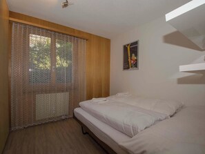 Ein Schlafzimmer mit einem Bett, einem Fenster mit Spitzenvorhängen und einem Poster an der Wand.