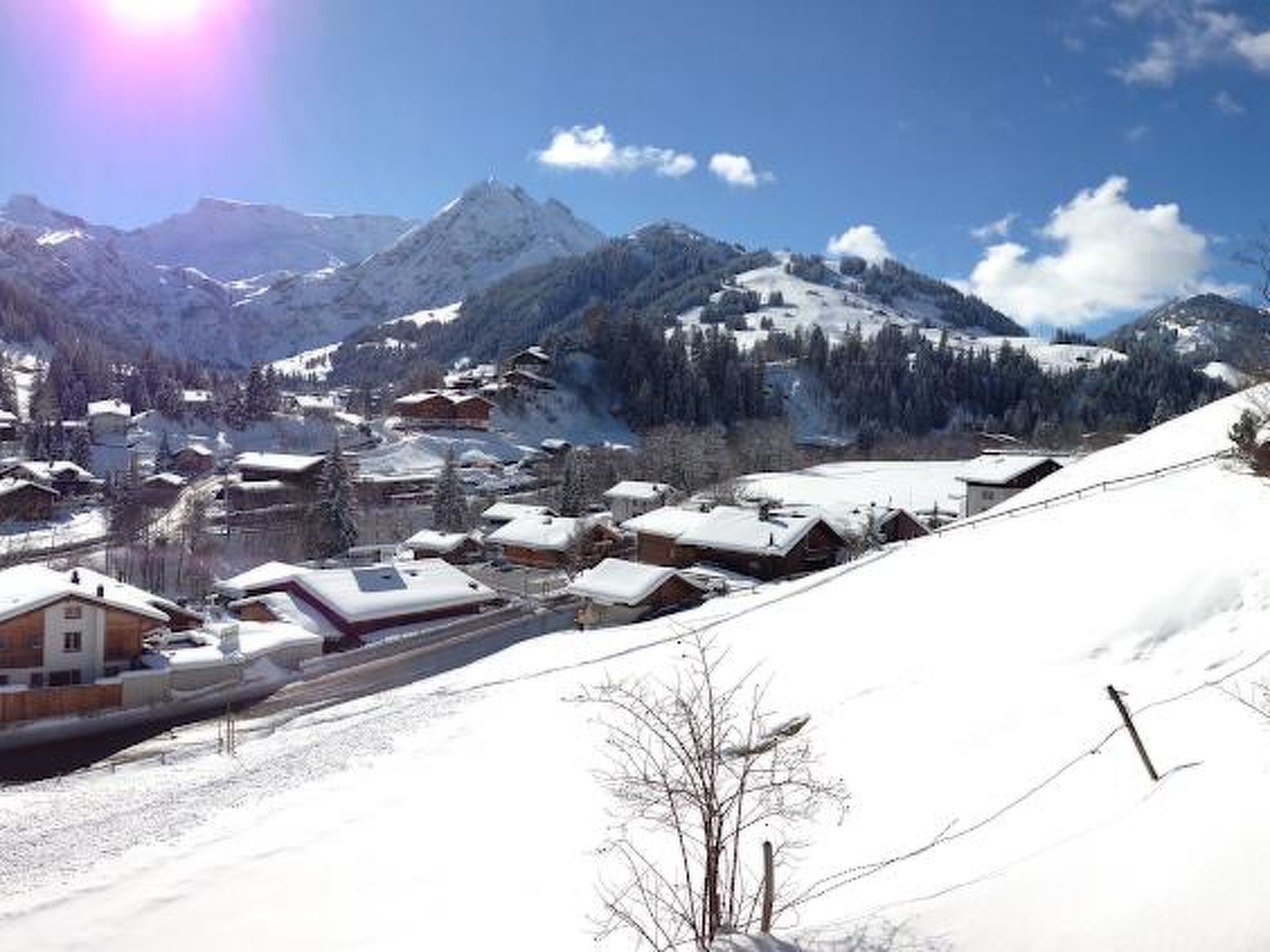 A snow-covered village with houses and mountains in the background.