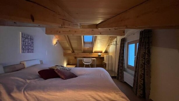 Un dormitorio con una cama grande, un escritorio y un tragaluz.