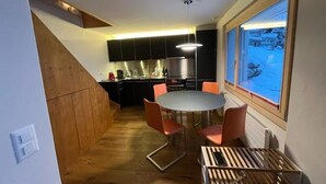Cocina compacta con comedor, piso de madera y vistas por una ventana.