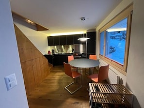 Eine kleine Küche mit Essbereich, Holzboden und Blick durch ein Fenster.