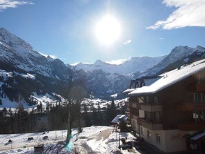 Ein Berggasthof mit Blick auf schneebedeckte Gipfel und einen klaren Himmel.