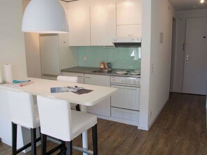 A compact kitchen with white cabinets, a dining table with chairs, and a single oven. - Studio Selva Appartement/Fewo, Dusche, WC, 1 Schlafraum 1-Zimmerwohnung by Interhome (Adelboden)