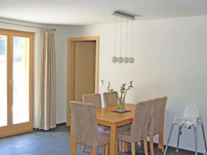 A dining area with a wooden table and chairs, a vase with flowers, and a hanging light fixture. - Schützenrain Appartement/Fewo, Bad, WC, 2 Schlafräume 3.5-Zimmerwohnung by Interhome (Adelboden)
