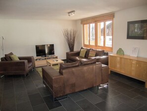 A living room with a flat-screen TV, two sofas, a coffee table, and a window with blinds. - Schützenrain Appartement/Fewo, Bad, WC, 2 Schlafräume 3.5-Zimmerwohnung by Interhome (Adelboden)