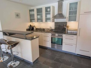 A modern kitchen with a central island, stainless steel appliances, and a bar stool. - Schützenrain Appartement/Fewo, Bad, WC, 2 Schlafräume 3.5-Zimmerwohnung by Interhome (Adelboden)