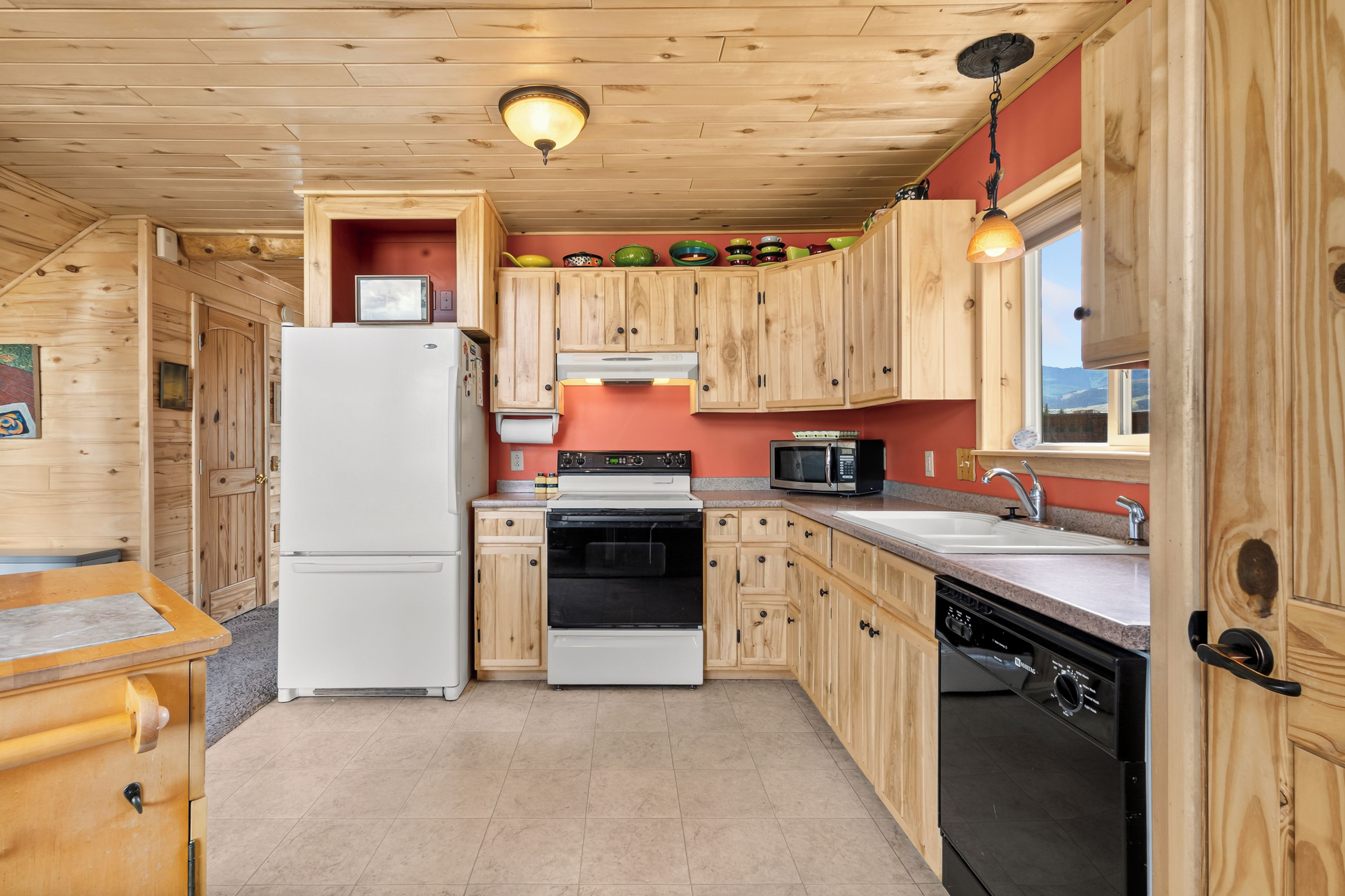 A compact kitchen with wooden cabinets, a refrigerator, stove, microwave, and dishwasher.