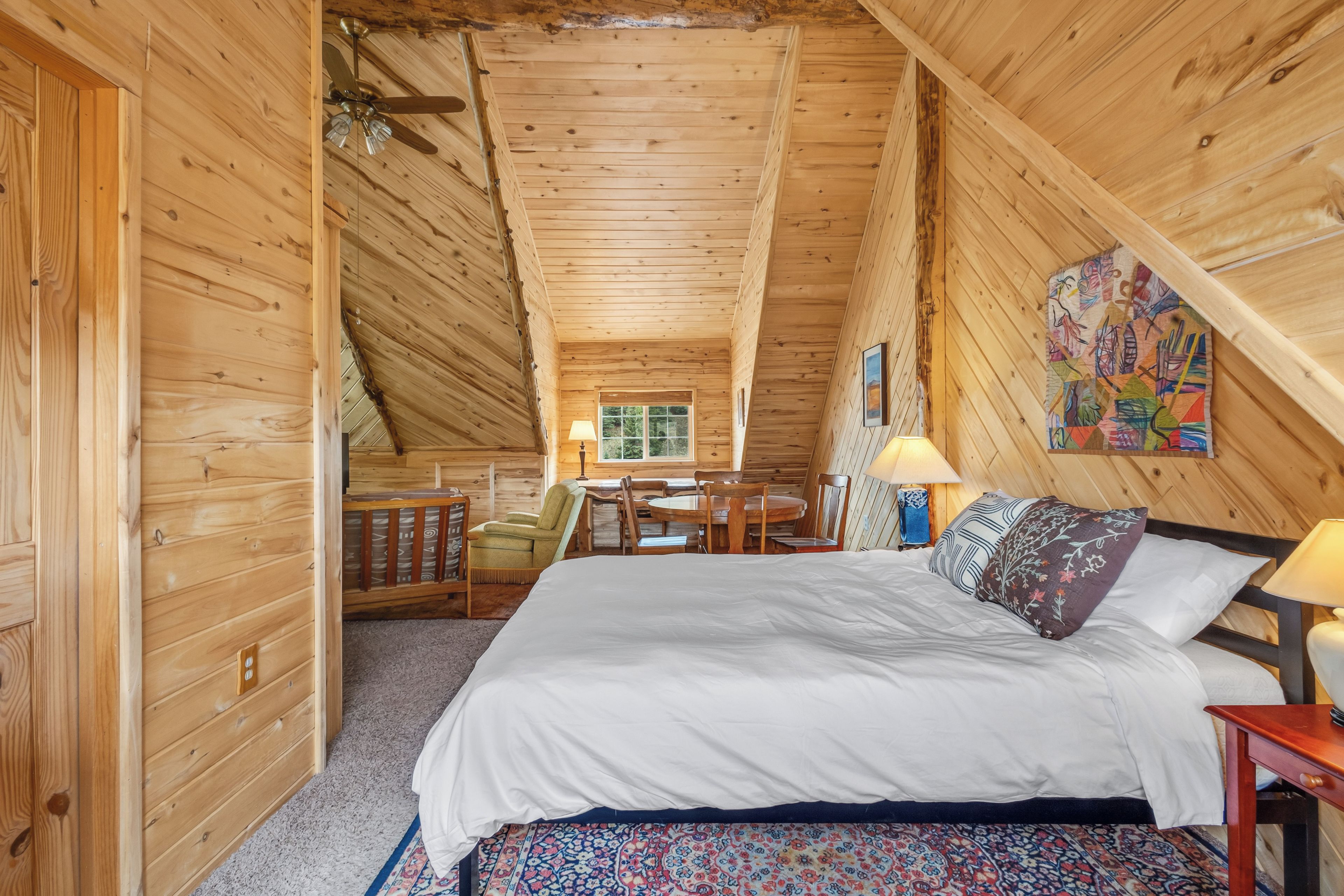 Een houten slaapkamer met een bed, een bureau en een stoel.