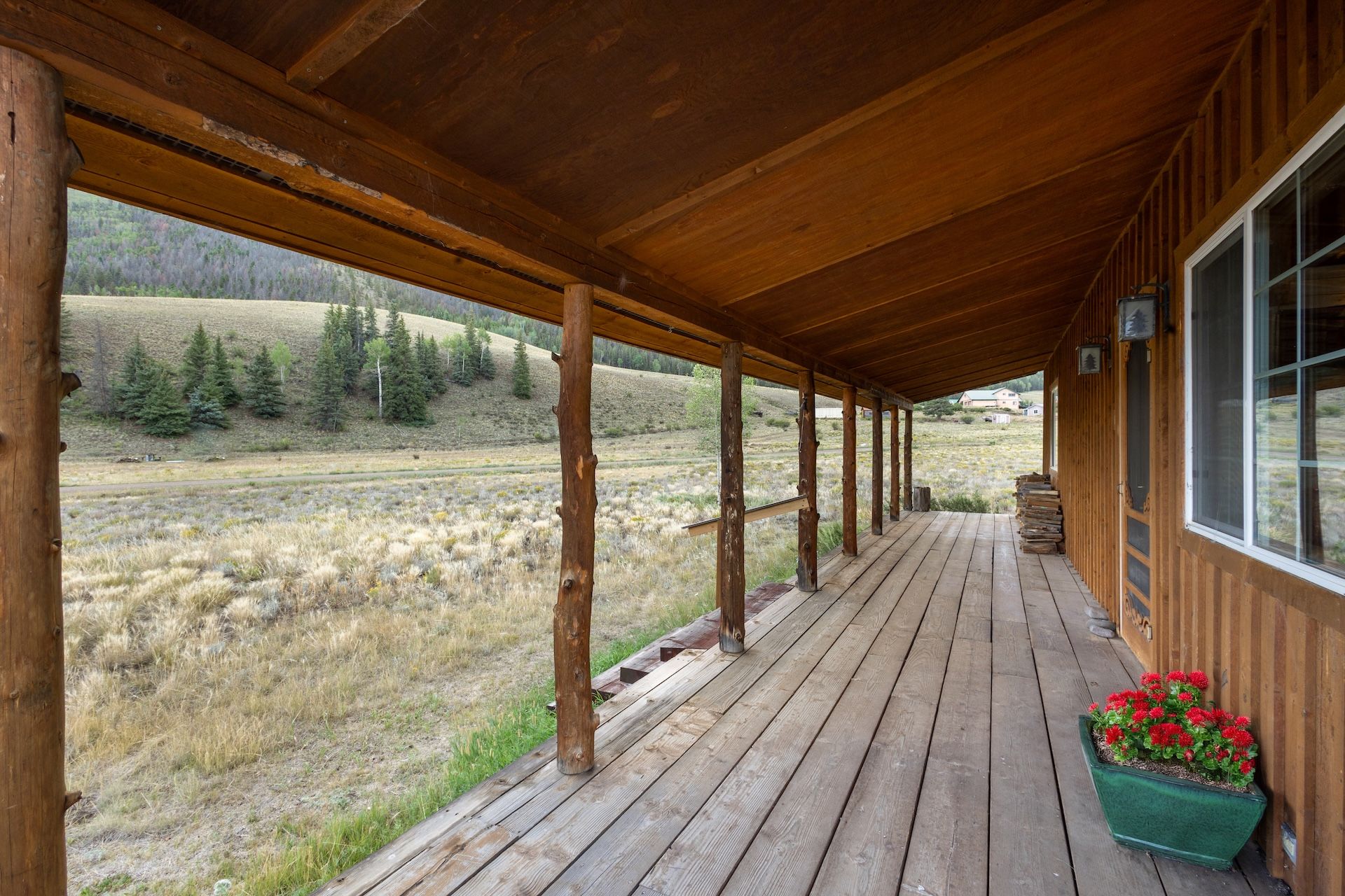 Un porche de madera con vistas a un campo cubierto de hierba y árboles.